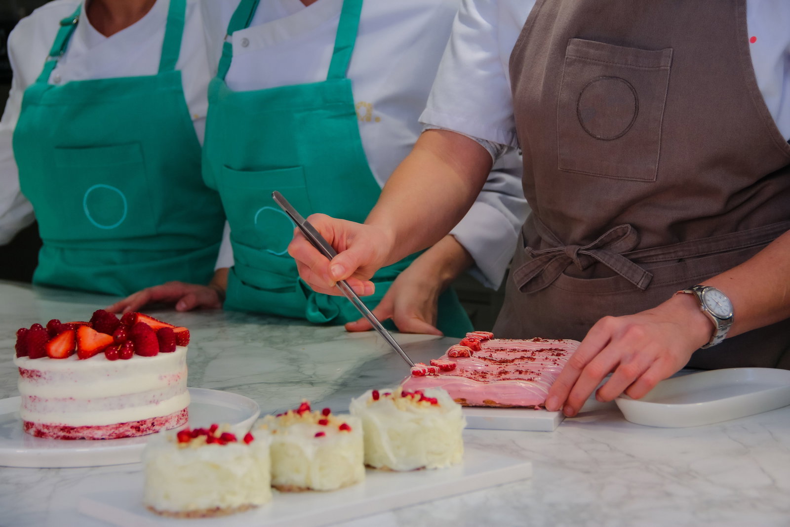 Konditoren mit Schürzen verzieren Törtchen