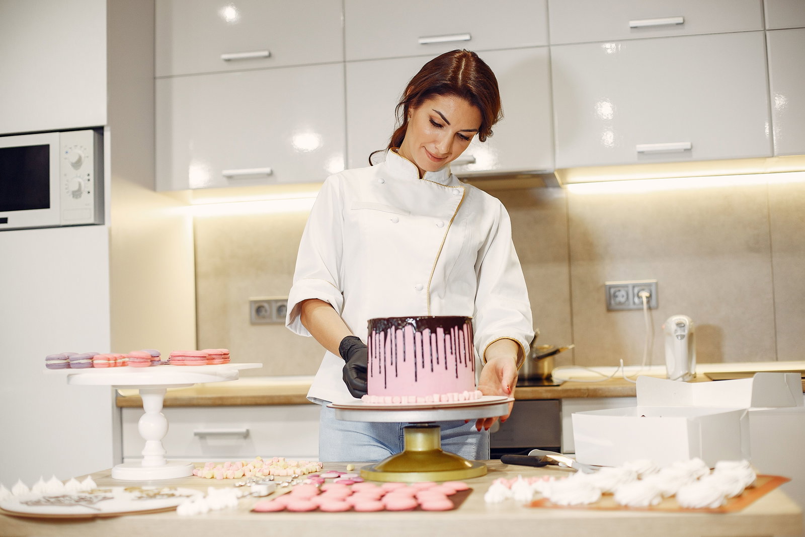Konditorin in weißer Kochuniform glaciert eine Torte