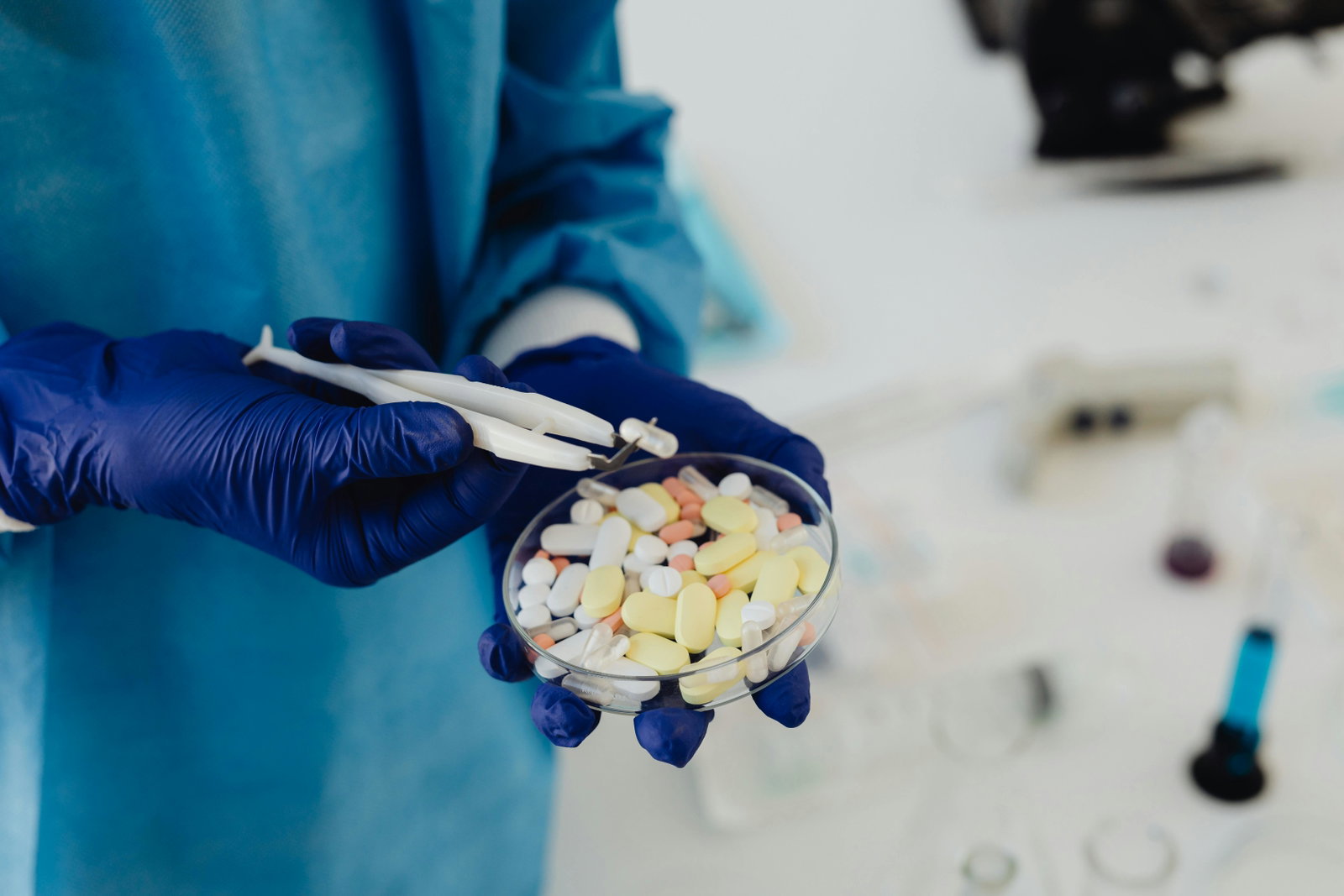 Pharmakant hält Becher mit Pillen und Tabletten in der Hand mit einem blauen Handschuh