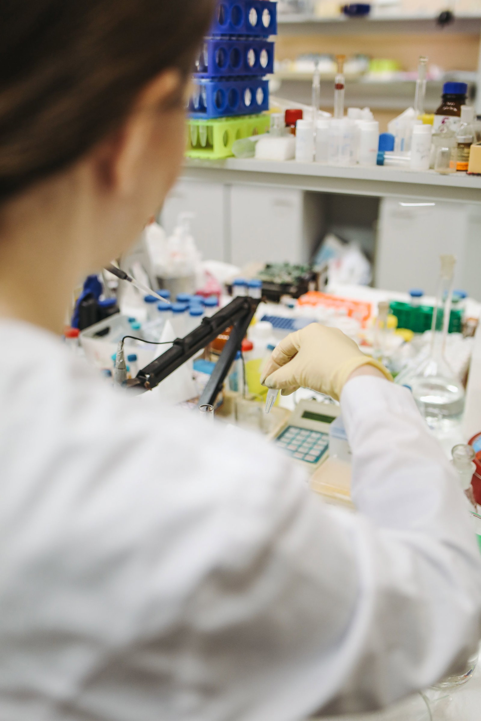 Pharmakant von hinten bei der Arbeit mit Pipette an einem Labortisch