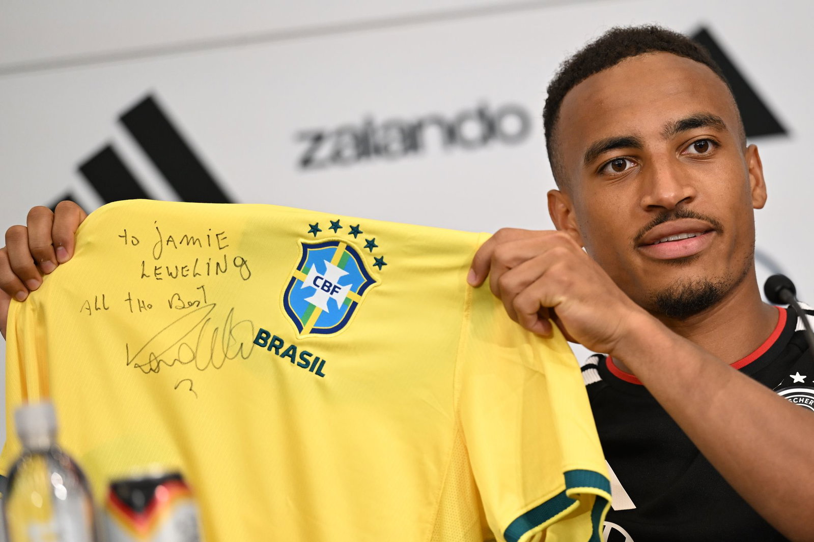 Jamie Leweling zeigt das Brasilien-Trikot mit der Unterschrift von Ronaldo. 