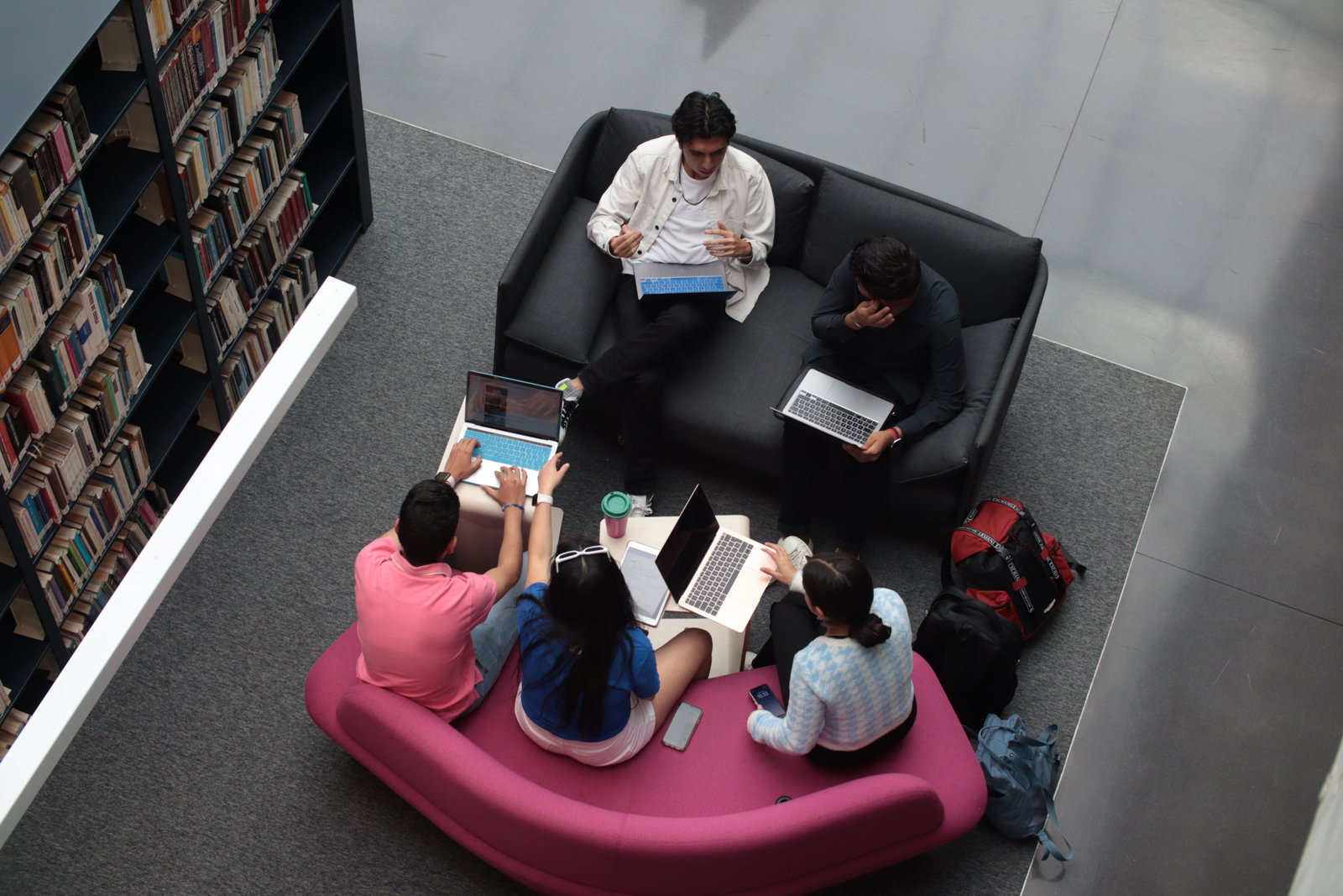 Gruppe jugendlicher in der Bibliotheken auf zwei Sofas und alle sind am Laptop 