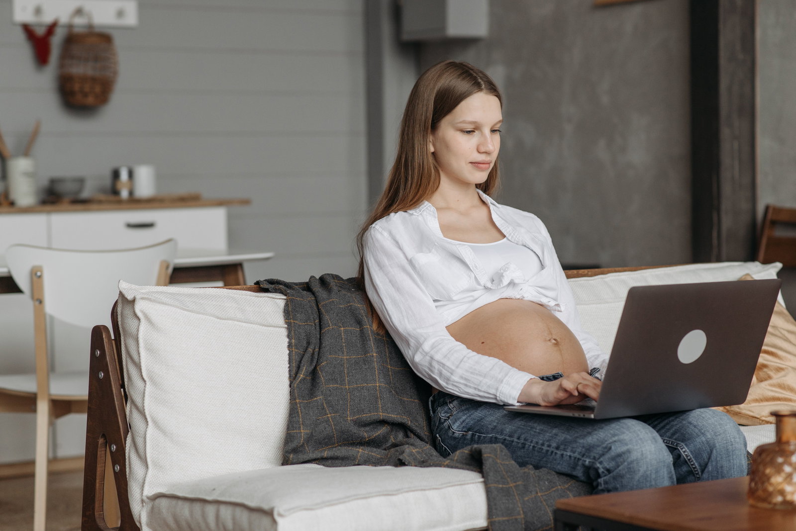 schwangere Frau auf Sofa an PC
