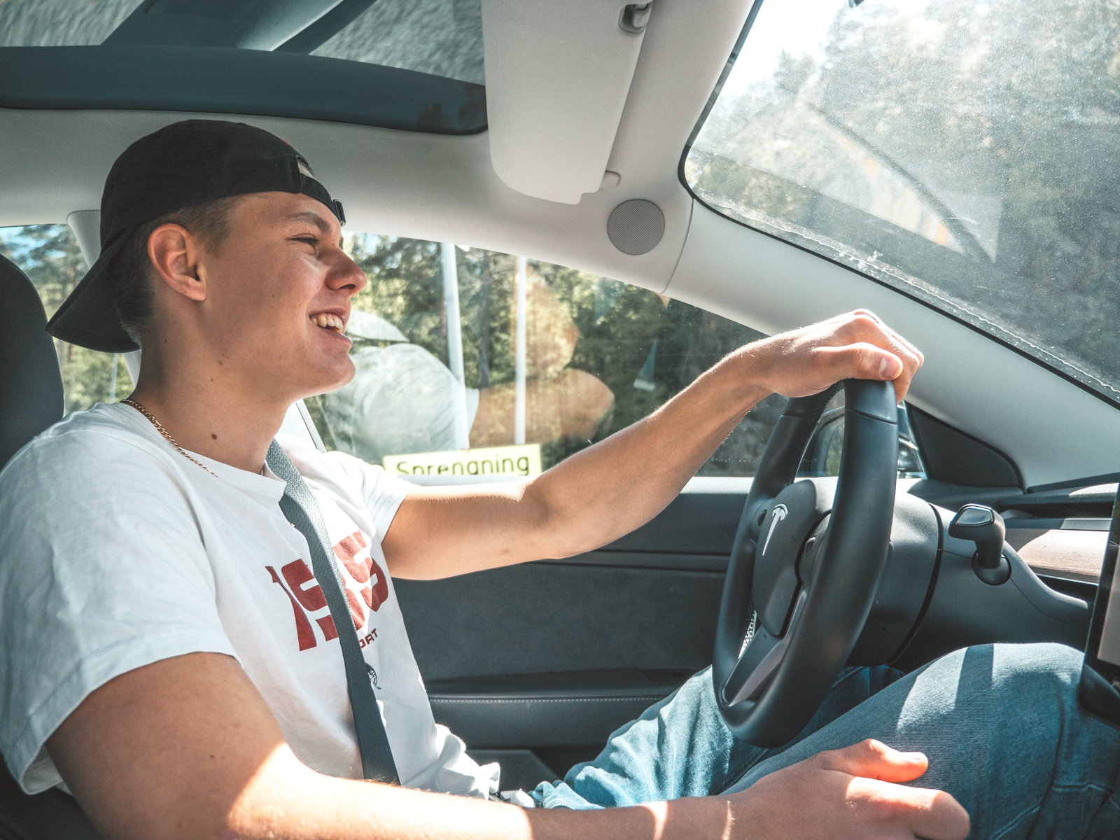 Mann sitzt am Steuer und fährt Auto, Mann trägt Käppi