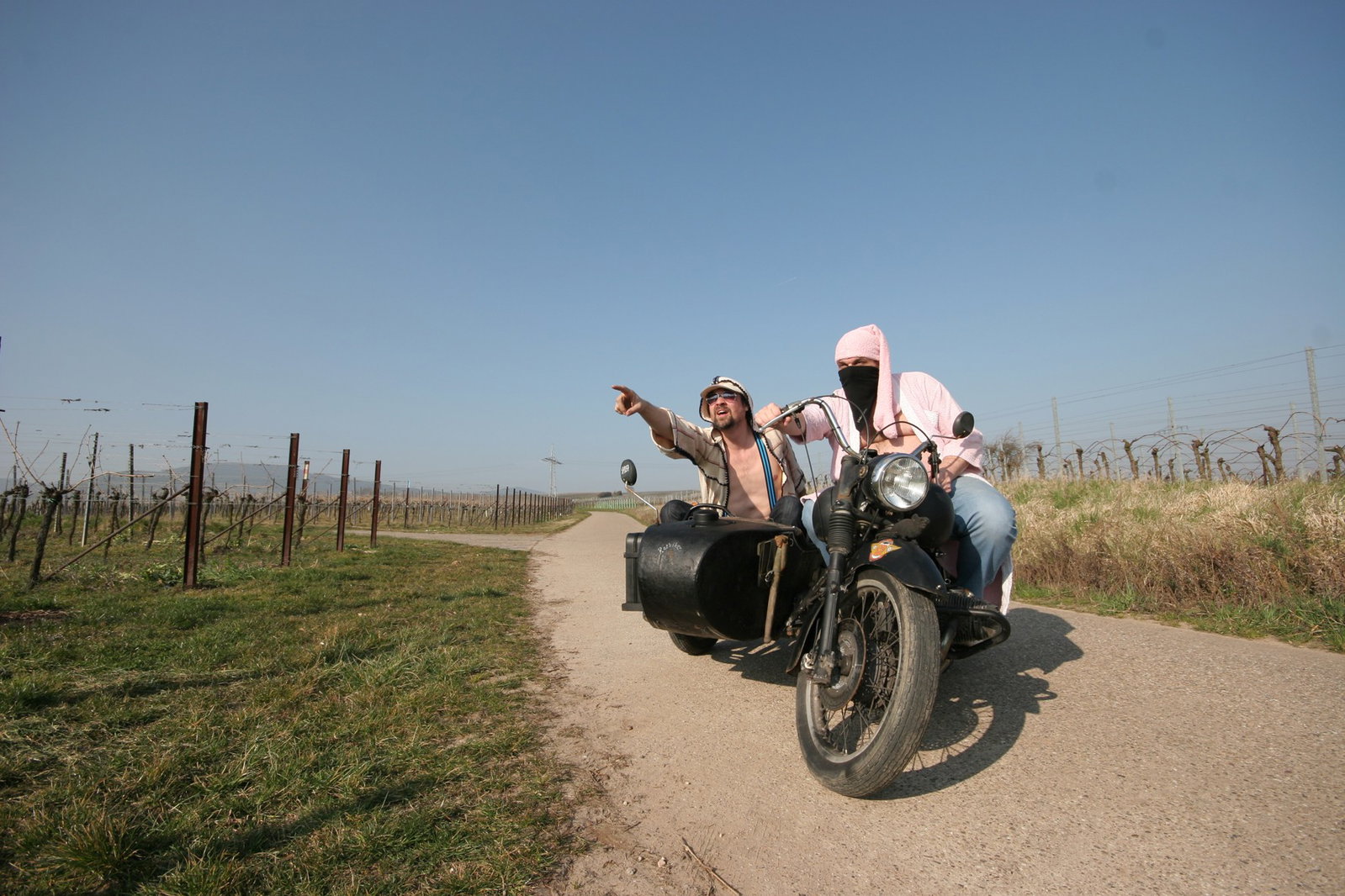 GELD ET NELT auf einem Motorrad zwischen den Wingert