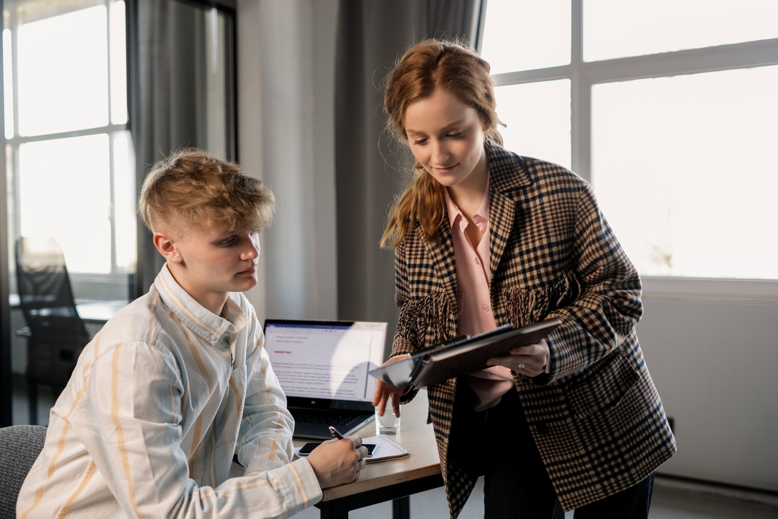 Managementassistentin erklärt einem Mitarbeiter etwas und hält ein Tablet in der Hand