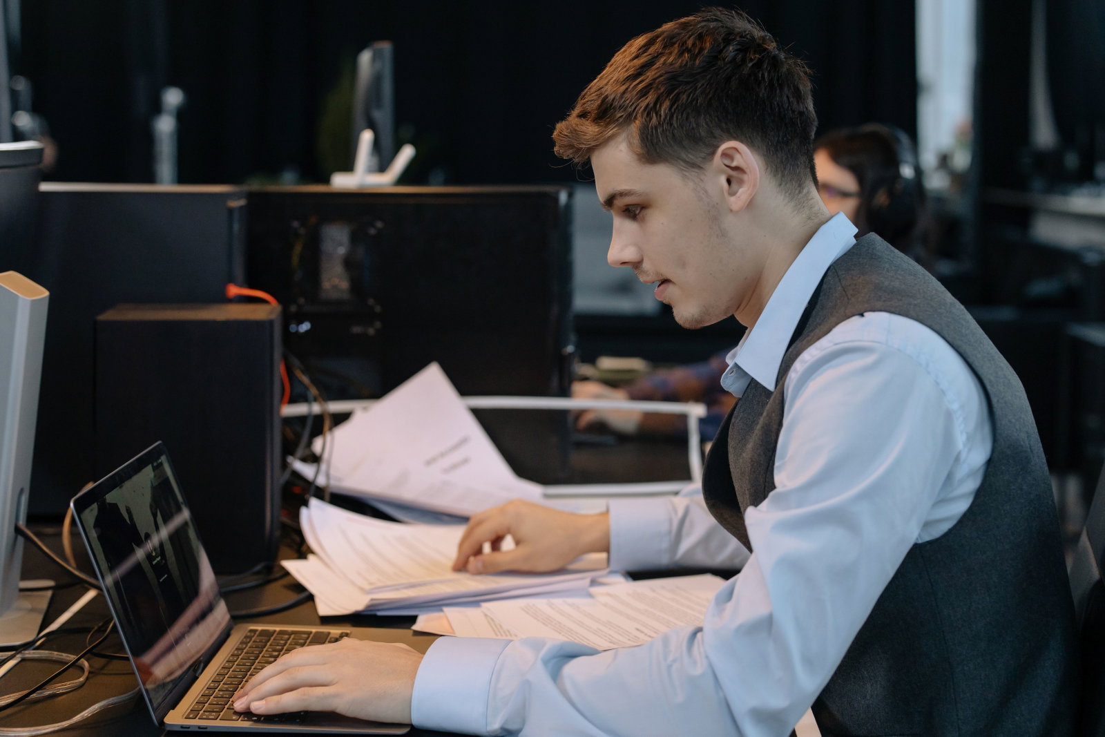 Managementassistent sitzt am Schreibtisch und schaut in ausgedruckte Dokumente