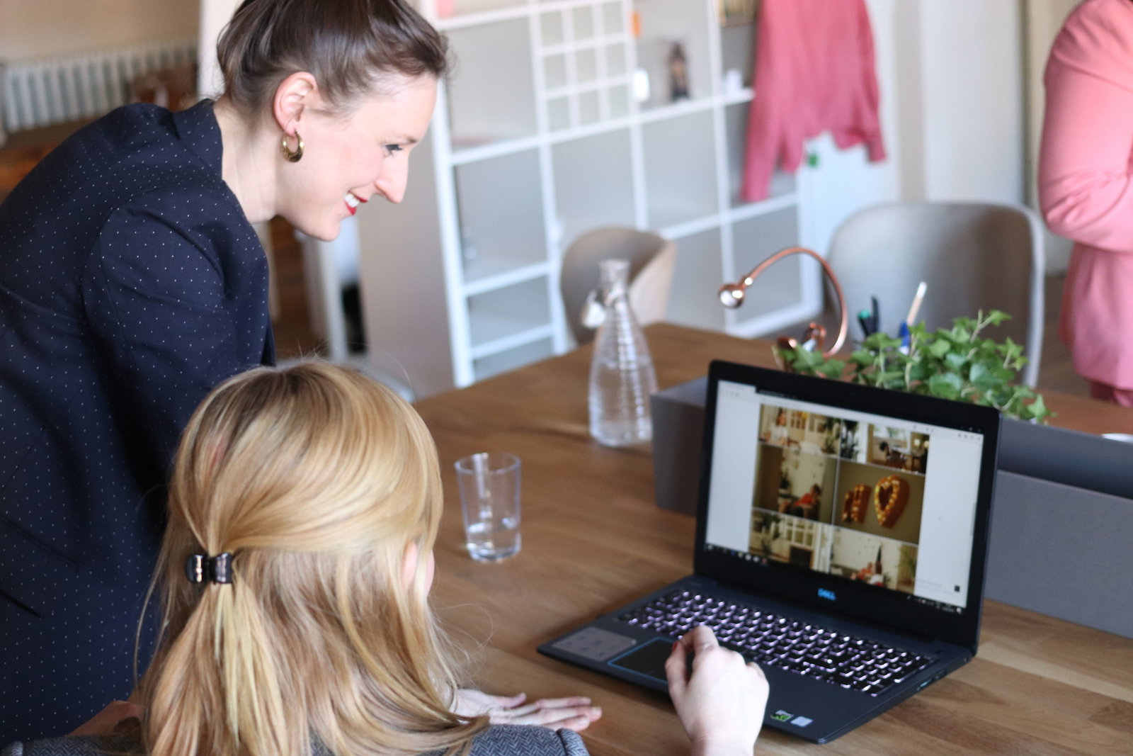 Managementassistentin schaut in einen Laptop und bekommt von einer Kollegin erklärt