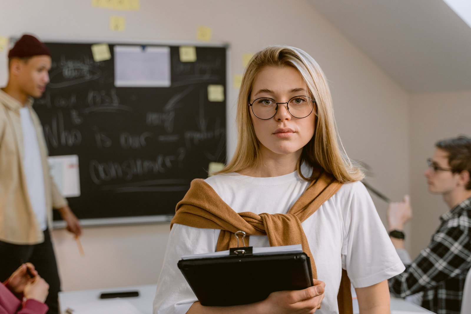Managementassistentin schaut in die Kamera und trägt eine Brille und hält Bücher