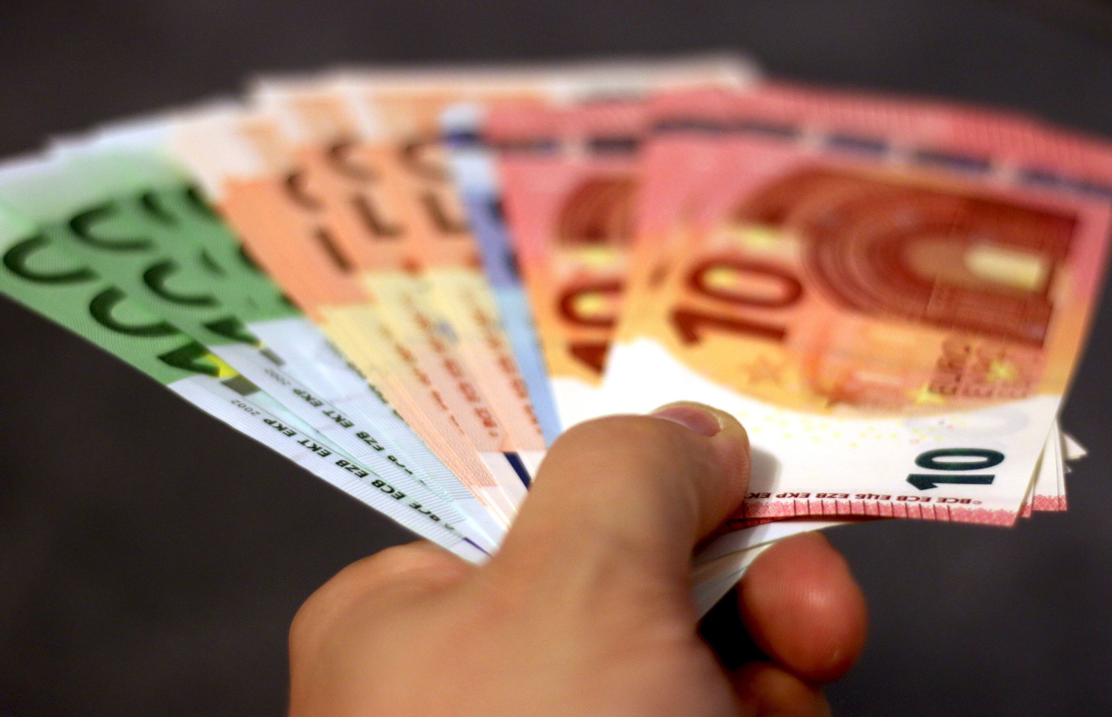 Hand mit verschiedensten Geldscheinen