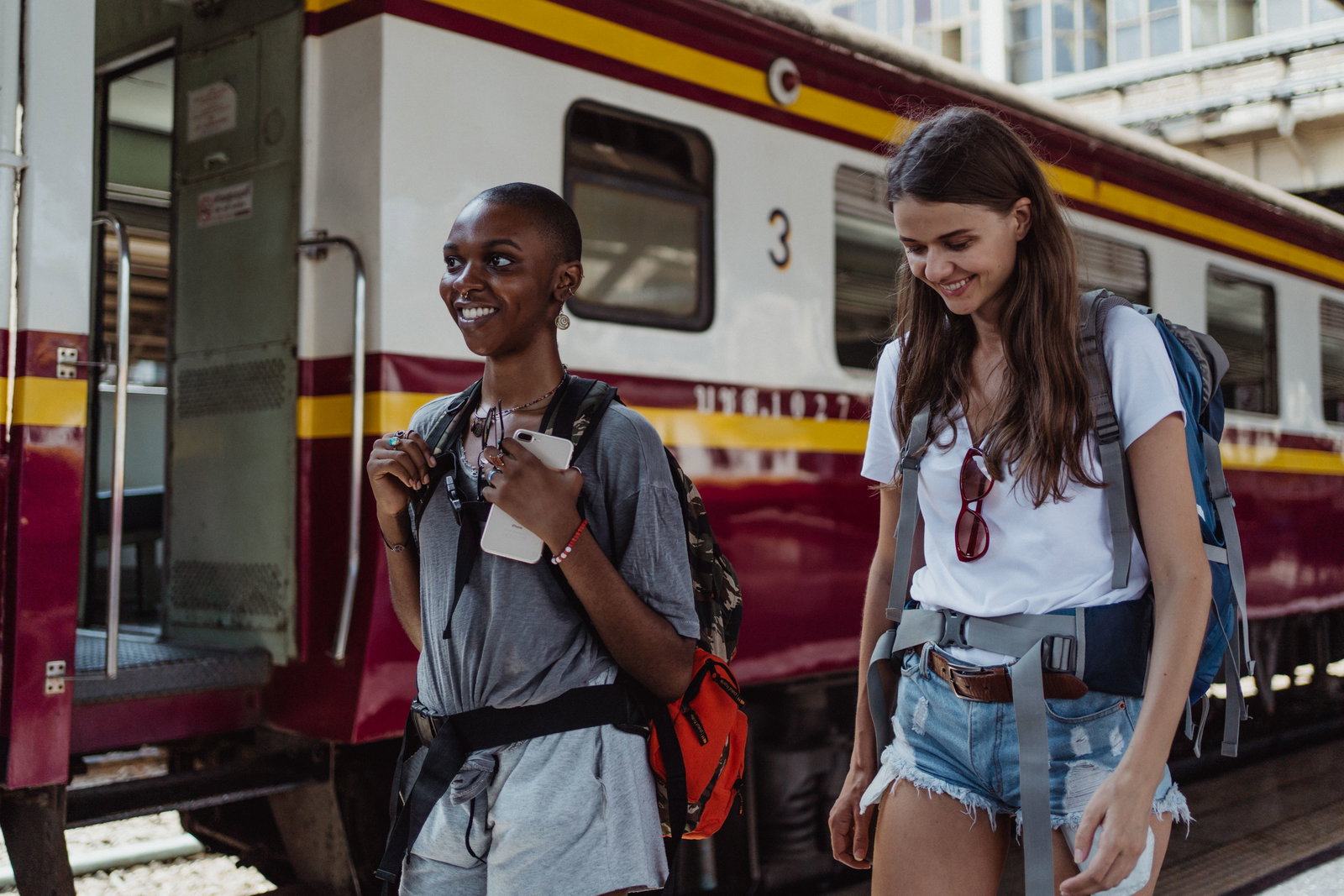 zwei Frauen laufen an Bahngleis, neben den Frauen steht ein Zug