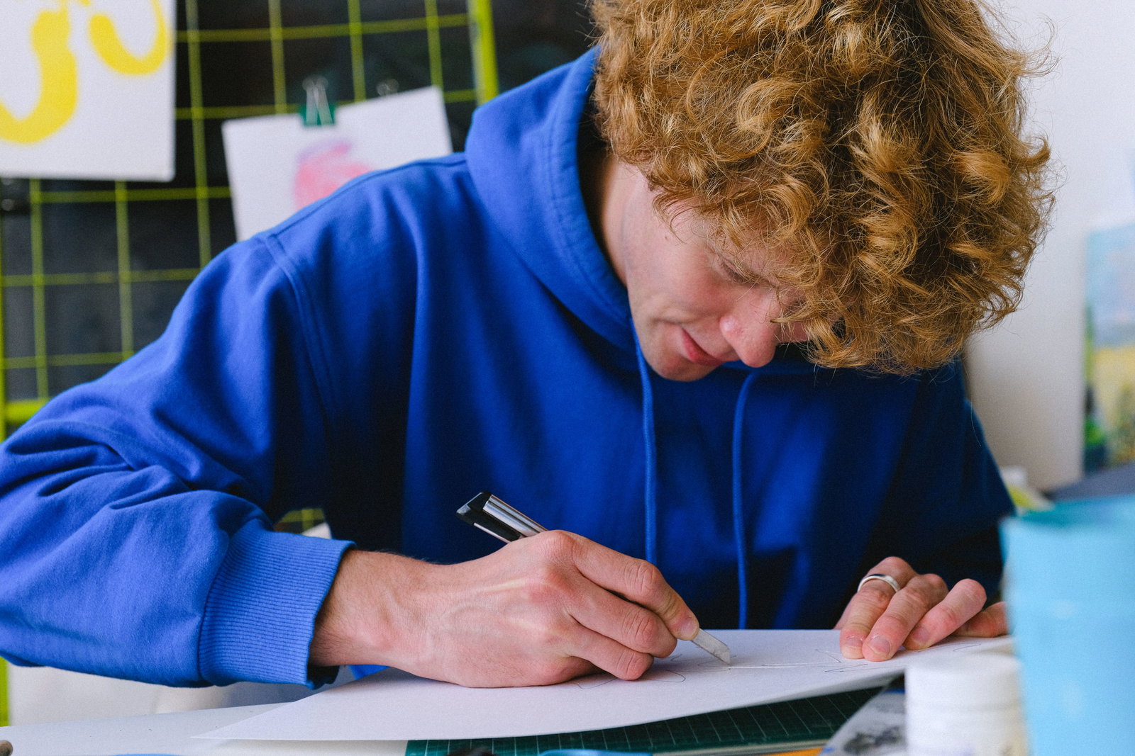 Mann mit Wuschelhaaren und blauem Pullover schreibt 