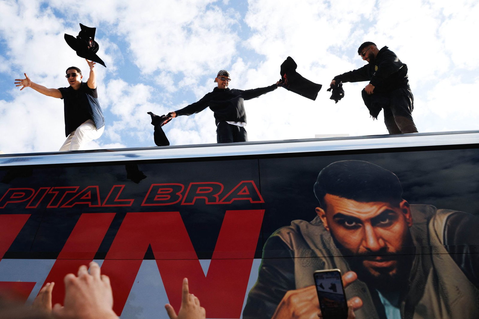 Die Rapper Lacazette, Capital Bra und Samra werfen bei einer Fanaktion in Kreuzberg T-Shirts von einem Tourbus. 