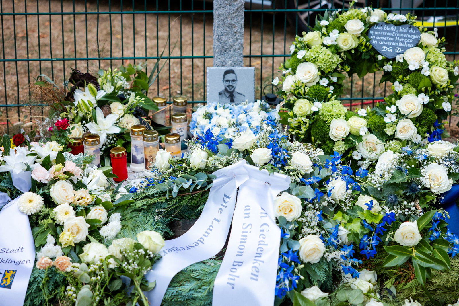 Vier Kränze stehen an der Gedenkstele für den getöteten Polizeioberkommissar Simon Bohr. Sie wurden von der Gewerkschaft der Polizei (GdP), der Deutschen Polizeigewerkschaft (DPolG), der Stadt Völklingen und dem saarländischen Innenministerium niedergele…