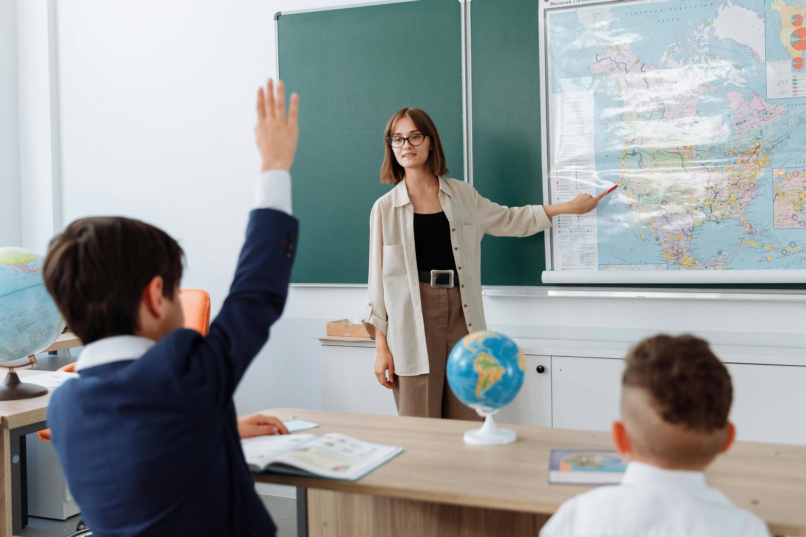 Lehrerin zeigt auf Tafel Kind meldet sich
