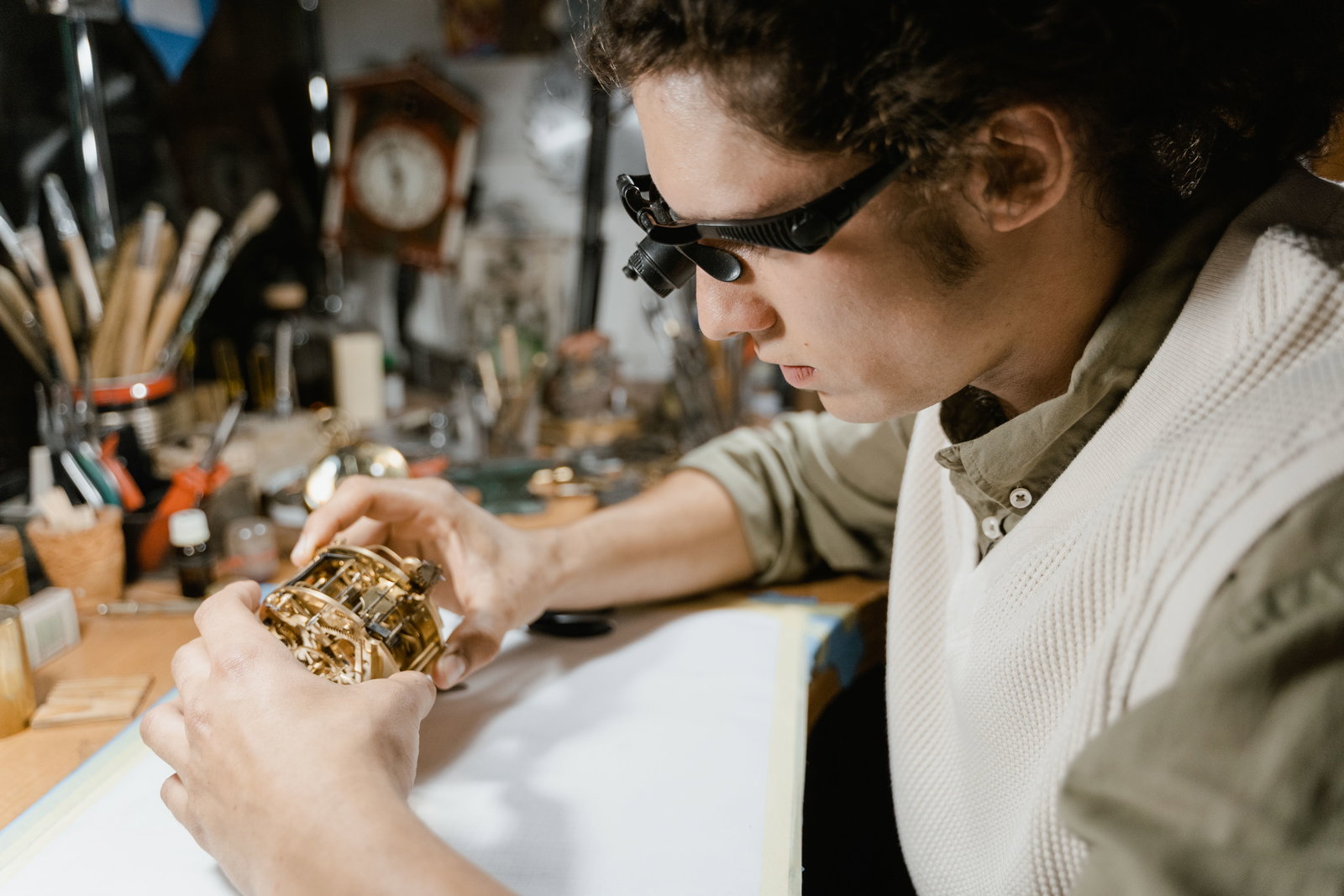 Goldschmied trägt eine Vergrößerungsbrille und schaut sich Gold an