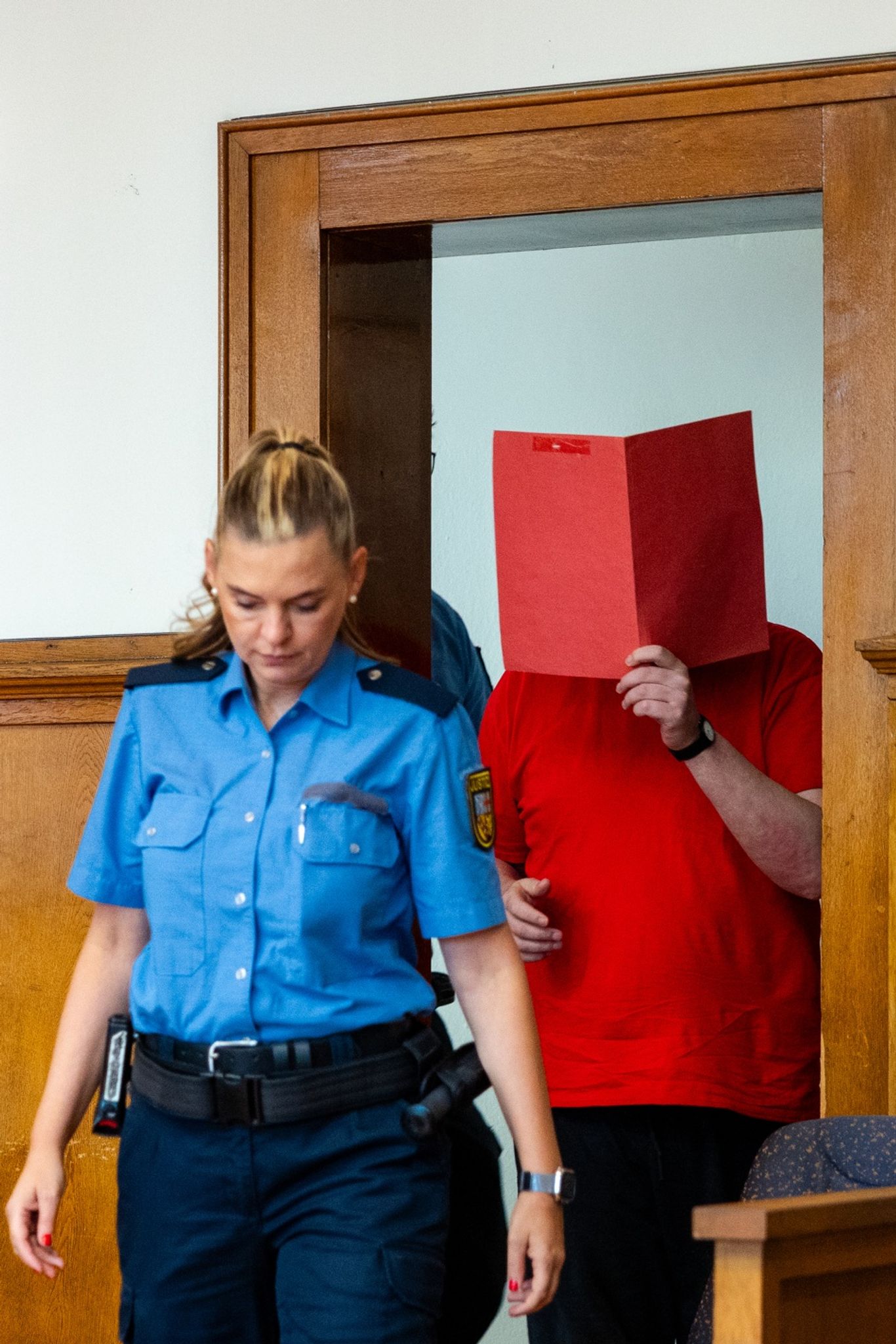 Der Angeklagte (r) wird von Justizvollzugsbeamten zur Urteilsverkündung in den Saal 38 des Landgerichts Saarbrücken geführt.
