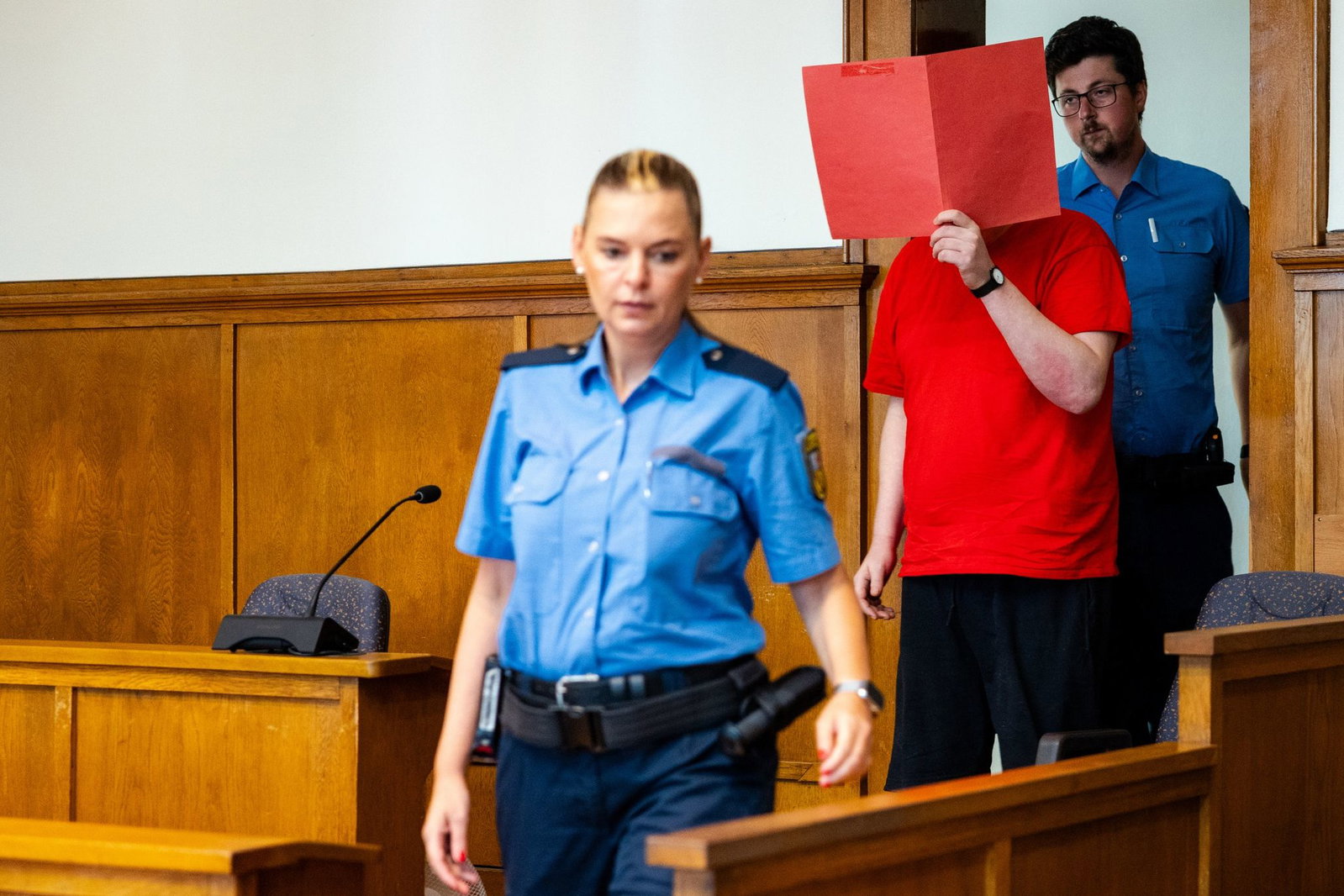 Der Angeklagte (M) wird von Justizvollzugsbeamten zur Urteilsverkündung in den Saal 38 des Landgerichts Saarbrücken geführt.