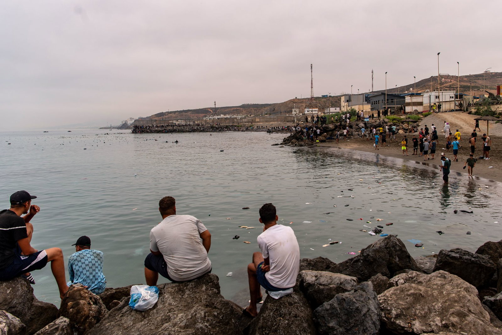 Migranten blickten von Felsen aus, während andere aus der spanischen Enklave Ceuta nach Marokko zurückkehrten.