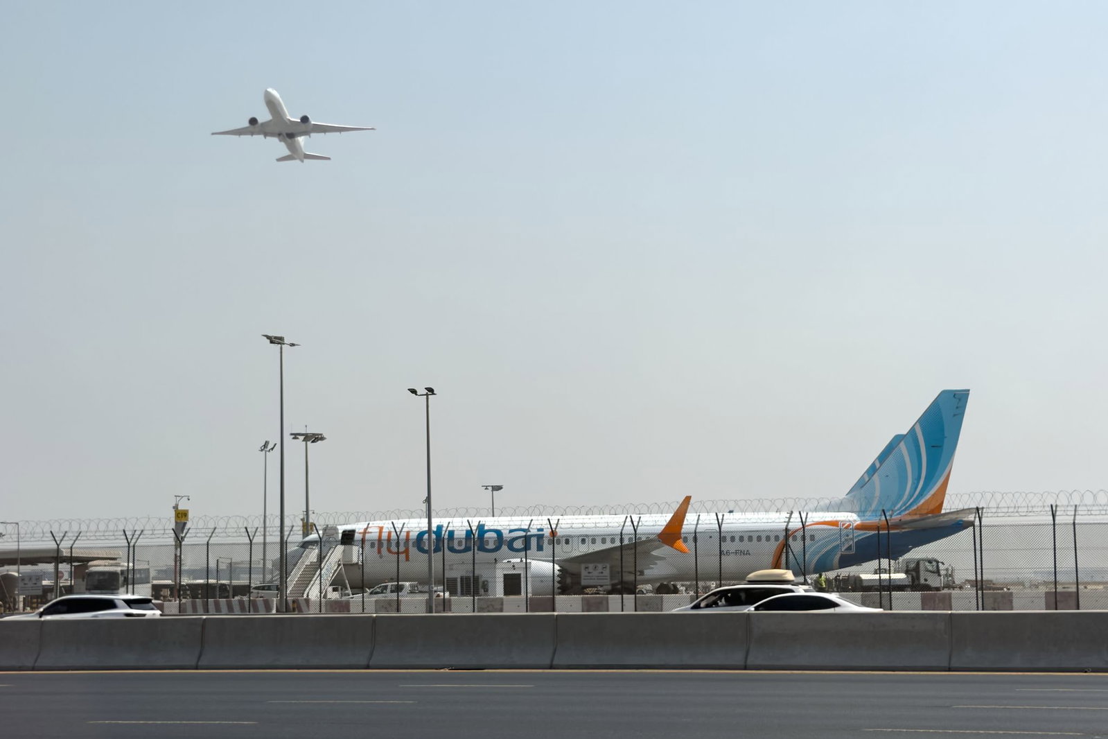Ein Flugzeug hebt ab, während ein Flydubai-Flieger in Dubai auf dem Flughafen steht. 