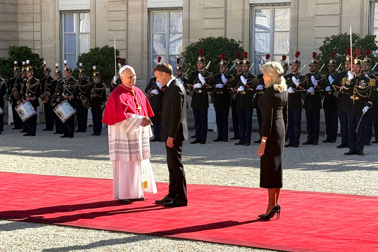 Frankreichs Präsident Emmanuel Macron und seine Ehefrau Brigitte schütteln Hände mit dem Papst im Hof des Élysée-Palastes.
