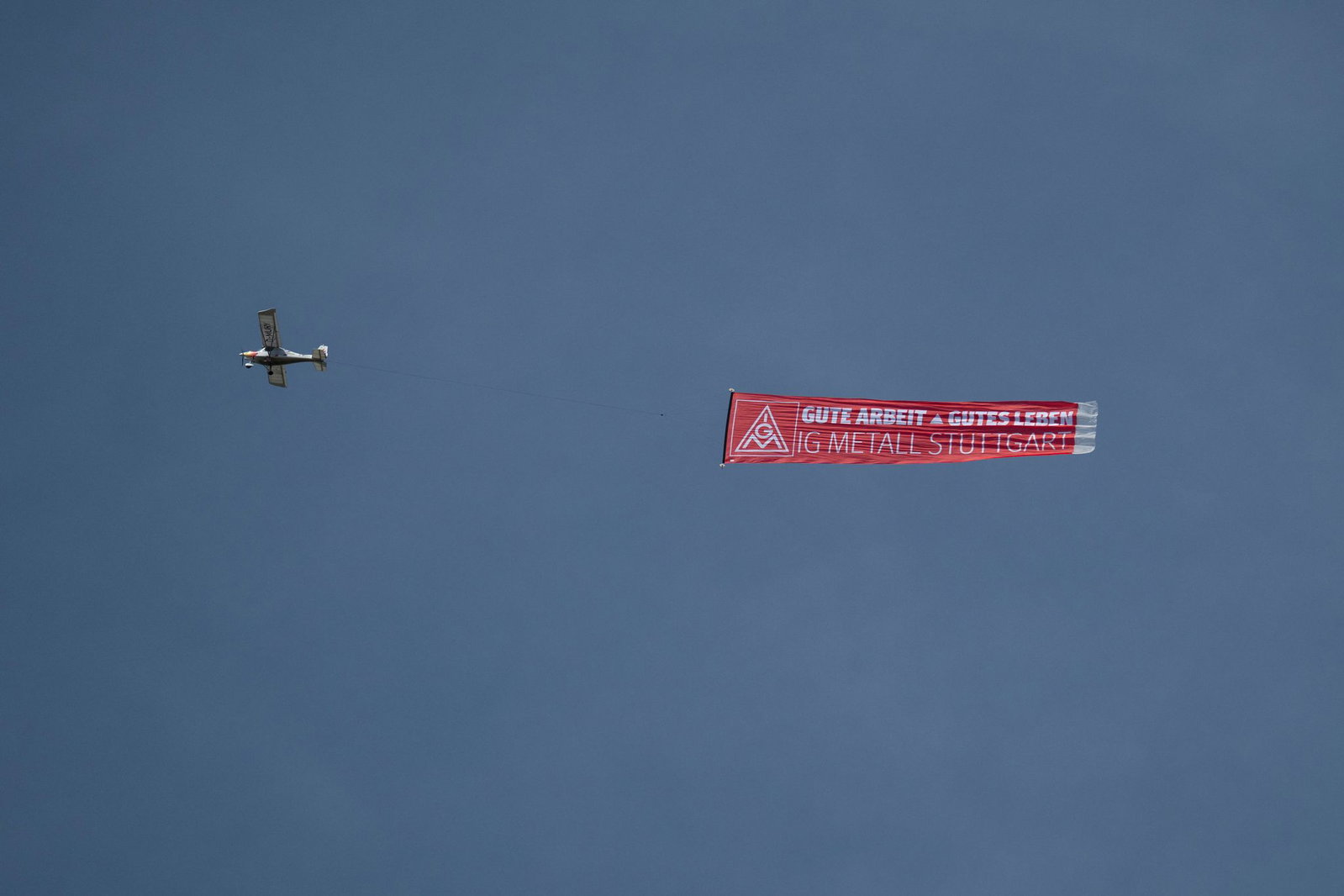 Ein Flugzeug mit einem IG-Metall-Banner fliegt über das Porsche-Stammwerk in Zuffenhausen.