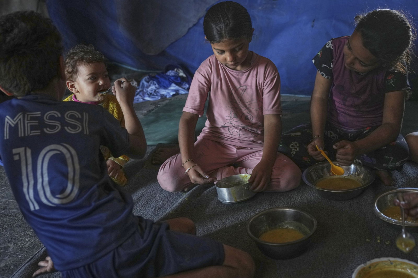 Kinder der Familie Saqr essen am Samstag, den 24. Mai 2025, in einem Familienzelt in Gaza-Stadt Linsensuppe, die ihre Mutter zubereitet hat.