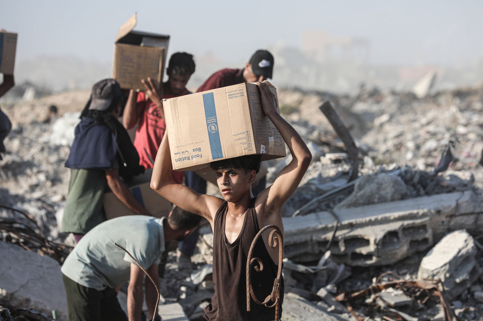 Palästinenser tragen ein Lebensmittelpaket, das von der „Gaza Humanitarian Relief Foundation“ verteilt wurde, während sie am 16. Juni 2025 in Gaza-Stadt mit Hunger infolge der anhaltenden israelischen Angriffe kämpfen. Die unter schwierigen Bedingungen le