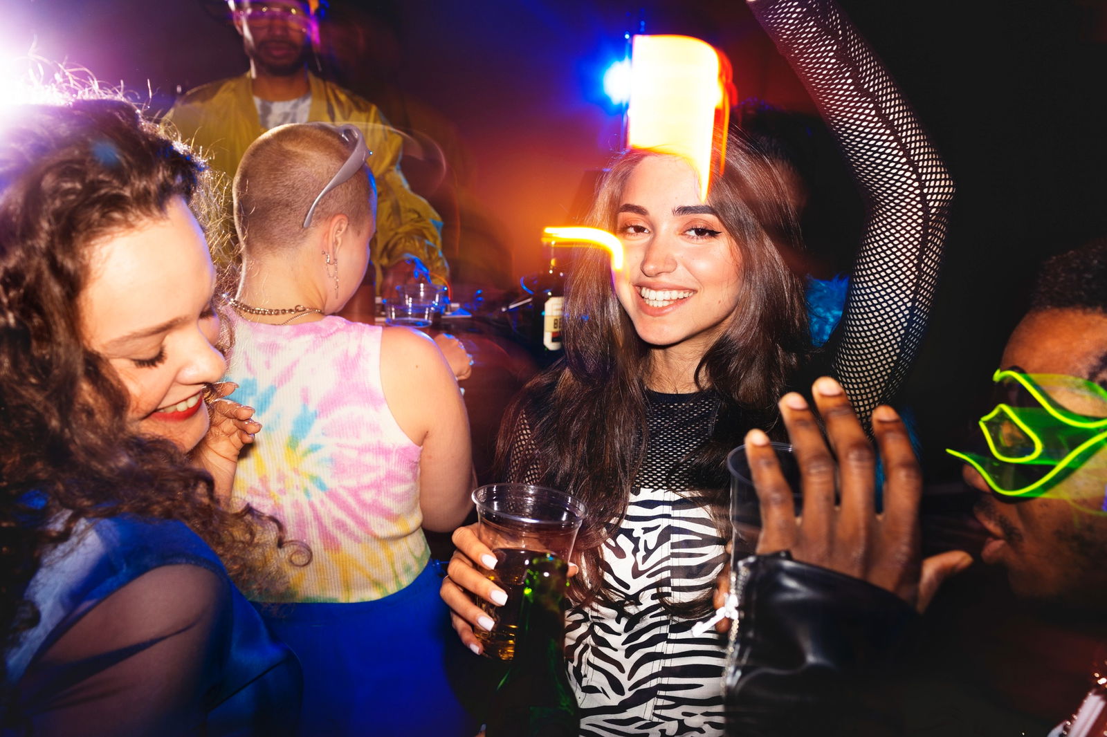 Junge Menschen tanzen und feiern bei bunter Beleuchtung - ausgelassene Stimmung auf einer Clubparty. Morning Rave Pre Work Party 